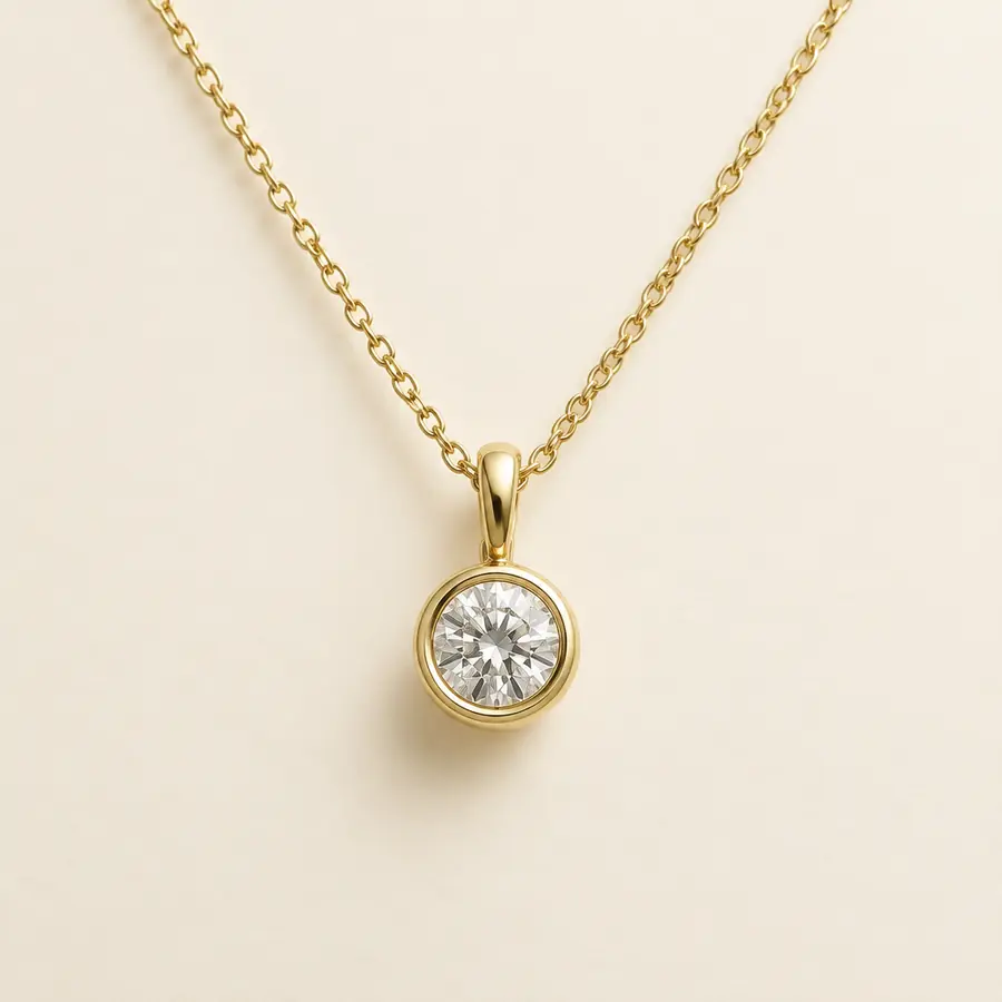 Bezel set round diamond pendant on a yellow gold cable chain